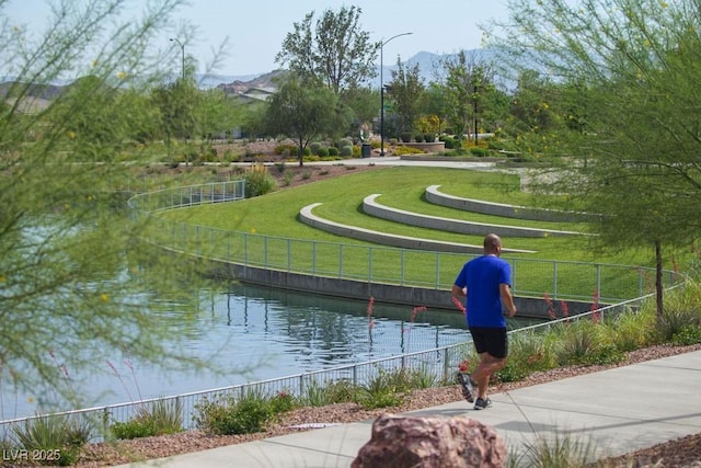 surrounding community with fence, a water and mountain view, and a yard