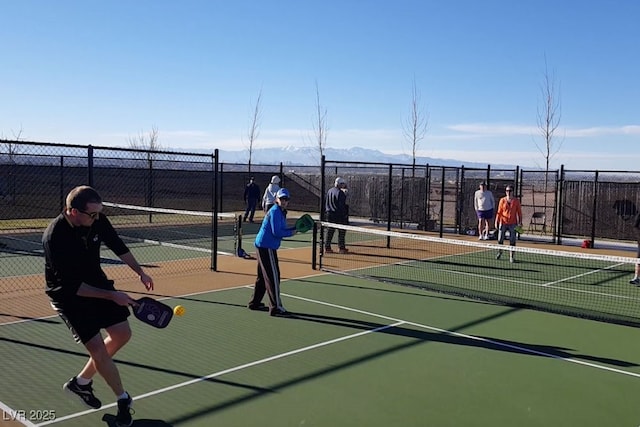 view of tennis court with community basketball court and fence