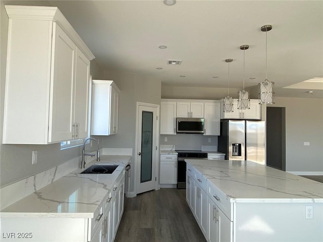 kitchen featuring stainless steel appliances, a sink, white cabinets, a center island, and decorative light fixtures