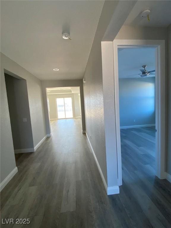 hallway featuring baseboards and dark wood finished floors