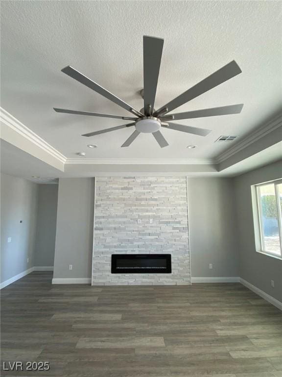 unfurnished living room featuring a textured ceiling, ornamental molding, a raised ceiling, and dark wood finished floors