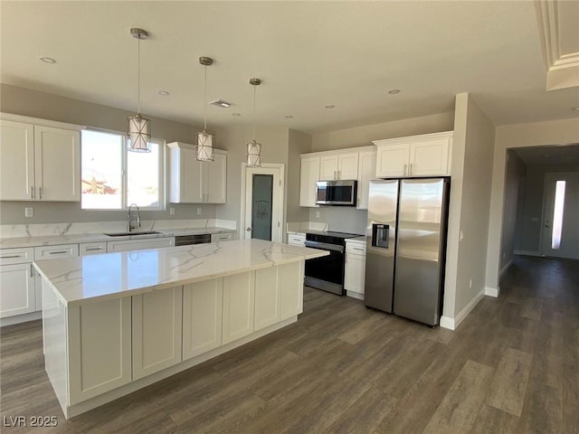 kitchen featuring appliances with stainless steel finishes, white cabinets, a sink, and a center island