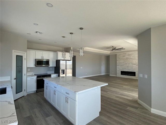 kitchen featuring white cabinets, open floor plan, stainless steel appliances, and a center island