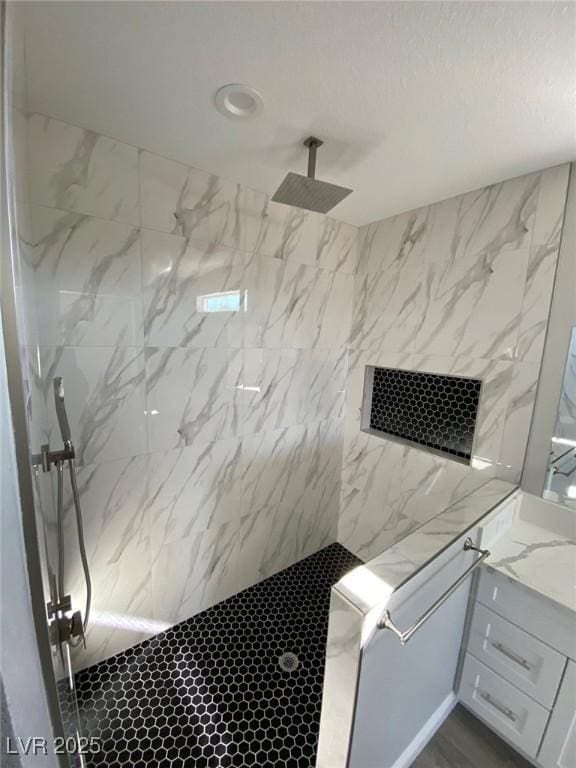 full bath featuring a marble finish shower and vanity