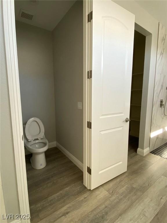 full bath with toilet, wood finished floors, visible vents, baseboards, and a shower