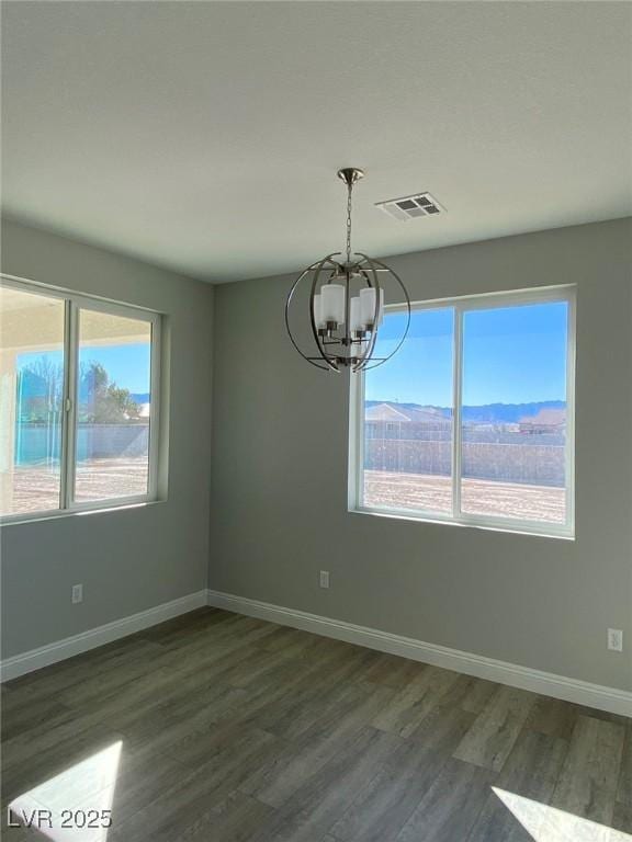 unfurnished dining area featuring baseboards, visible vents, dark wood finished floors, a chandelier, and a mountain view