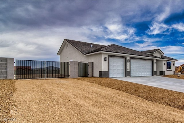 view of side of property featuring stucco siding, a gate, fence, concrete driveway, and a garage