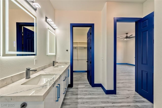 full bath with double vanity, wood finished floors, a sink, and baseboards