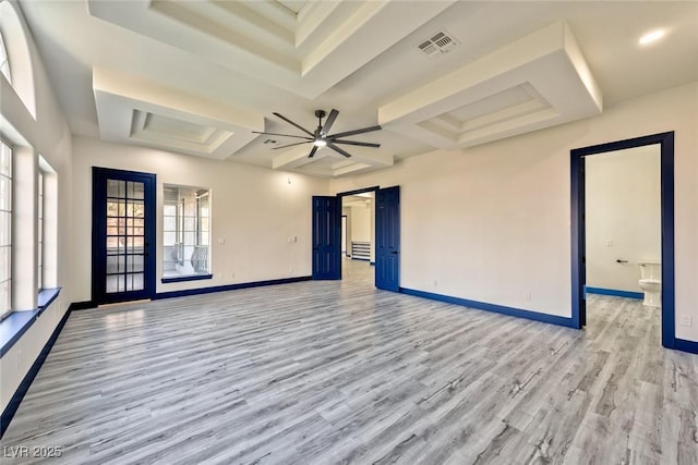 spare room with a barn door, light wood-style floors, visible vents, and baseboards