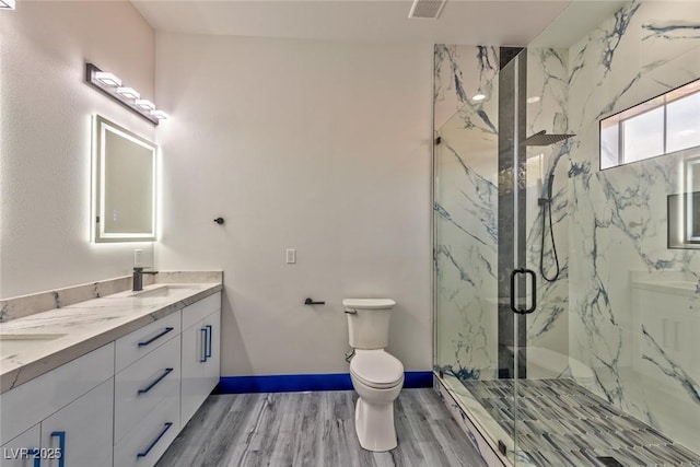 bathroom featuring a marble finish shower, visible vents, toilet, wood finished floors, and a sink