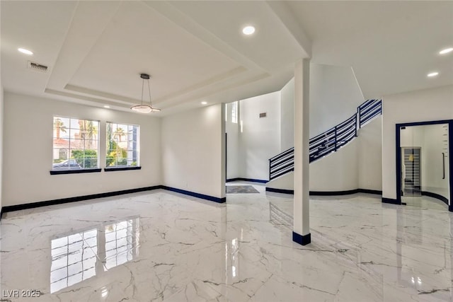 spare room with marble finish floor, visible vents, a tray ceiling, and baseboards