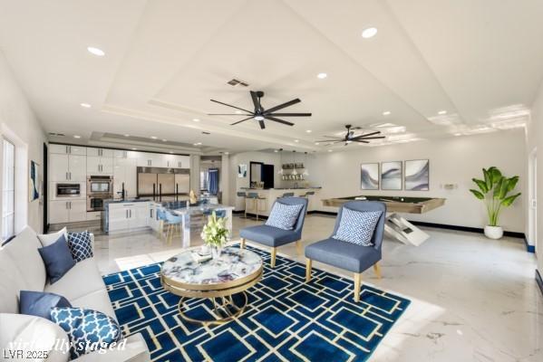 living area with recessed lighting, a raised ceiling, visible vents, and marble finish floor