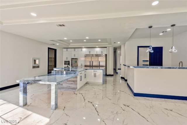 kitchen with stainless steel appliances, visible vents, white cabinets, hanging light fixtures, and a raised ceiling