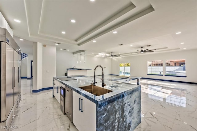 kitchen featuring a tray ceiling, a spacious island, a sink, and white cabinets