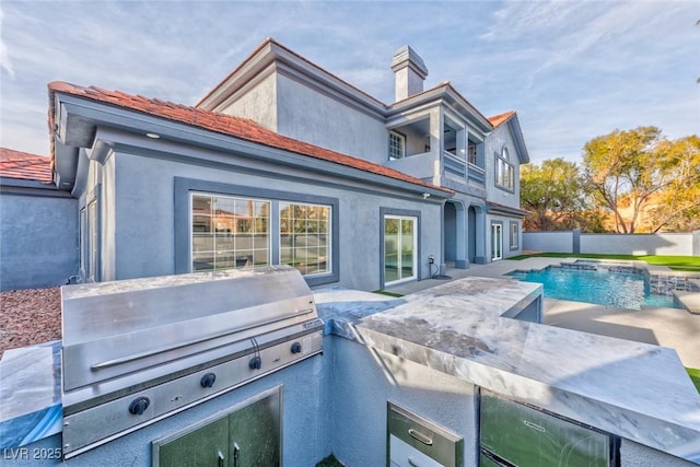 exterior space with exterior kitchen, a fenced in pool, and stucco siding