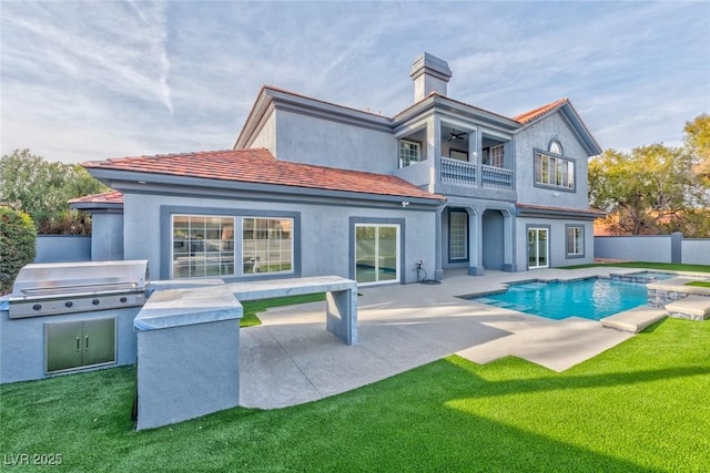 back of house with a fenced in pool, stucco siding, an outdoor kitchen, fence, and a balcony