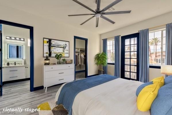 bedroom featuring ensuite bathroom, a ceiling fan, a spacious closet, a closet, and light wood finished floors