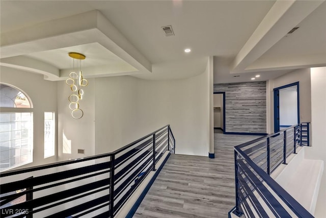 hallway with an accent wall, recessed lighting, visible vents, and an upstairs landing