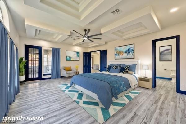 bedroom with visible vents, a barn door, light wood-style floors, connected bathroom, and access to outside