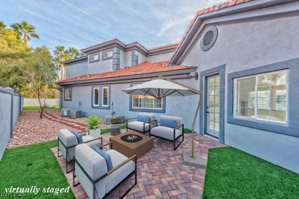 rear view of property with an outdoor living space with a fire pit, a fenced backyard, a patio, and stucco siding