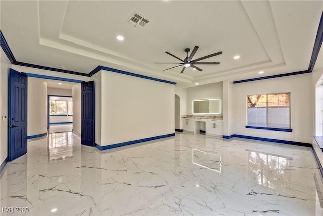 empty room with ornamental molding, a raised ceiling, visible vents, and baseboards