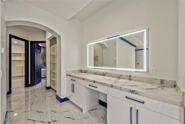 bathroom with marble finish floor, a spacious closet, and vanity