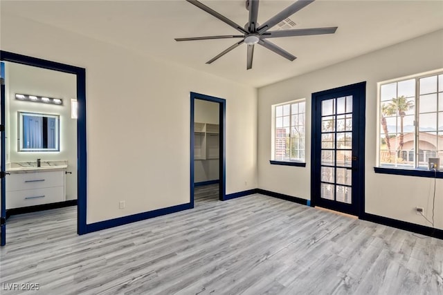 empty room featuring a ceiling fan, light wood-style flooring, and baseboards