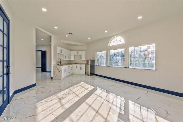 kitchen with a sink, white cabinets, marble finish floor, light countertops, and freestanding refrigerator