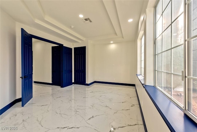 spare room featuring a tray ceiling, visible vents, plenty of natural light, and baseboards