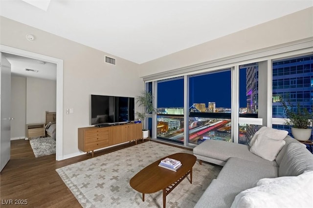 living room featuring visible vents, baseboards, and wood finished floors