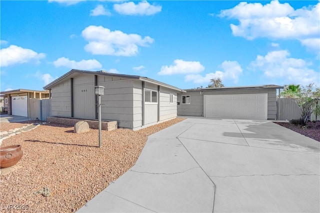 view of front of house with a garage, concrete driveway, and fence