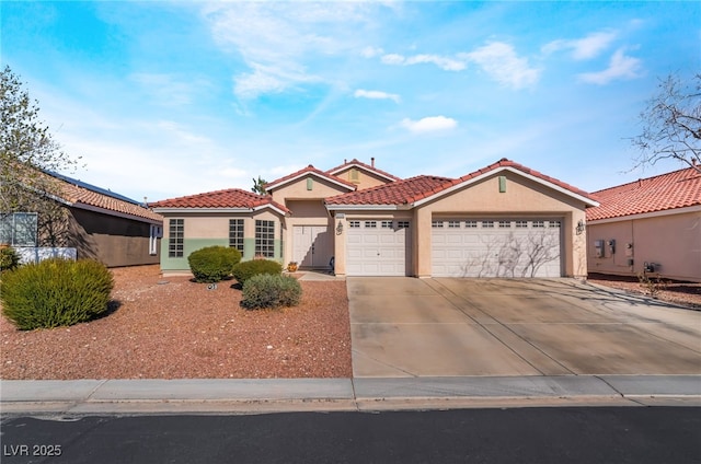 mediterranean / spanish-style house with a garage, a tiled roof, concrete driveway, and stucco siding