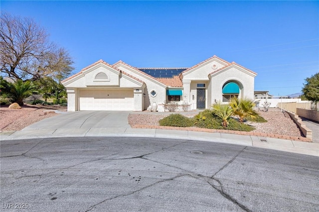 view of front facade featuring a garage, fence, driveway, roof mounted solar panels, and stucco siding