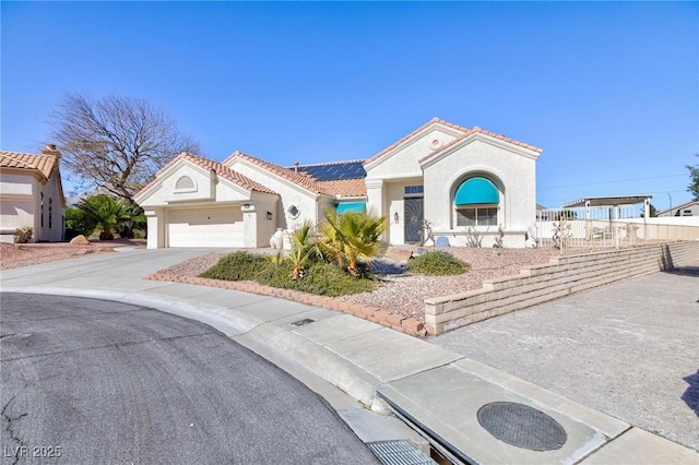 mediterranean / spanish-style home featuring solar panels, a tiled roof, concrete driveway, and stucco siding