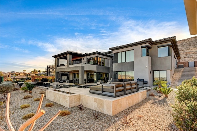 back of house featuring a balcony, an outdoor hangout area, stairs, a patio area, and stucco siding