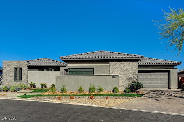 prairie-style home featuring a garage, driveway, a tiled roof, and stucco siding