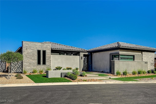 prairie-style house with a tile roof, fence, and stucco siding