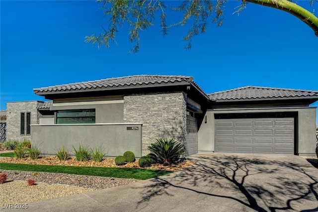 prairie-style house featuring aphalt driveway, an attached garage, and stucco siding