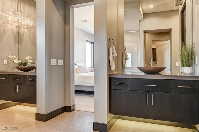 ensuite bathroom with ensuite bath, two vanities, a sink, and tile patterned floors