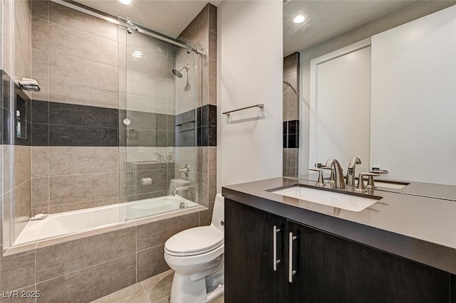 bathroom featuring tile patterned flooring, tiled shower / bath combo, vanity, and toilet