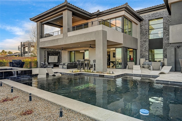 rear view of house with a patio, stucco siding, ceiling fan, a balcony, and fence