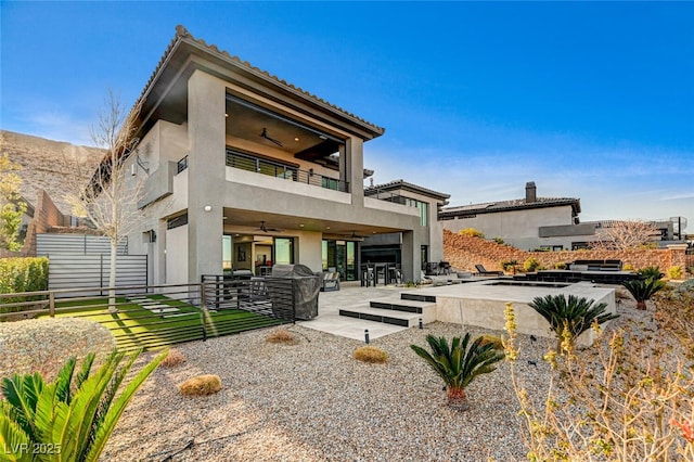 back of house with a patio, stucco siding, a ceiling fan, fence, and a balcony