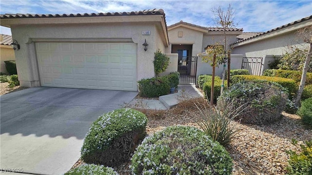 mediterranean / spanish-style home with driveway, an attached garage, a gate, and stucco siding