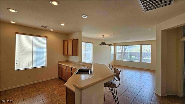 kitchen with a peninsula, a breakfast bar area, a sink, and visible vents