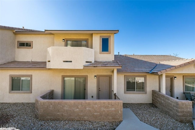 back of house with a tile roof and stucco siding