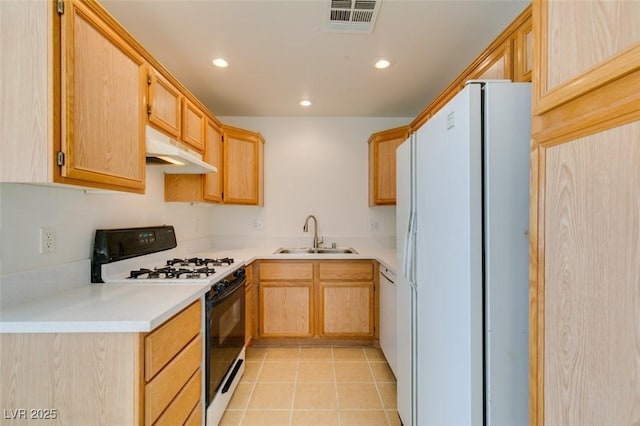 kitchen featuring under cabinet range hood, a sink, light countertops, freestanding refrigerator, and gas stove