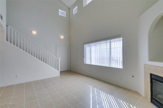 unfurnished living room with stairs, light tile patterned floors, a fireplace, and visible vents