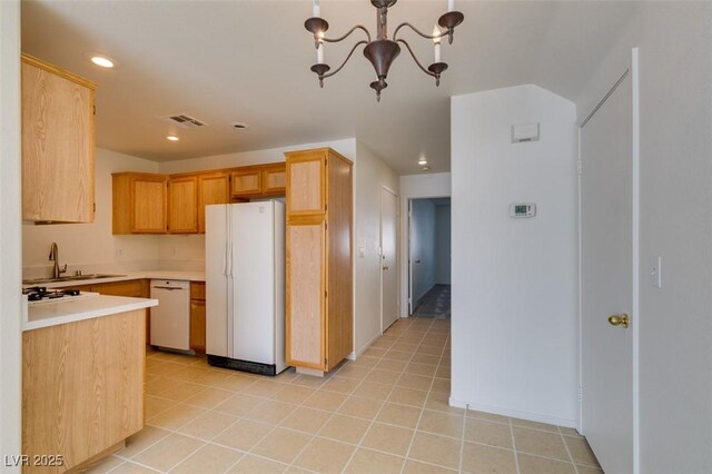 kitchen featuring a notable chandelier, white appliances, visible vents, light countertops, and light brown cabinetry