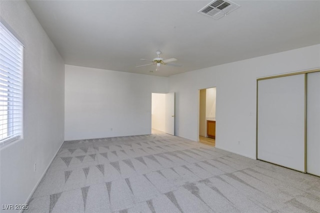 unfurnished bedroom featuring light carpet, visible vents, and a ceiling fan