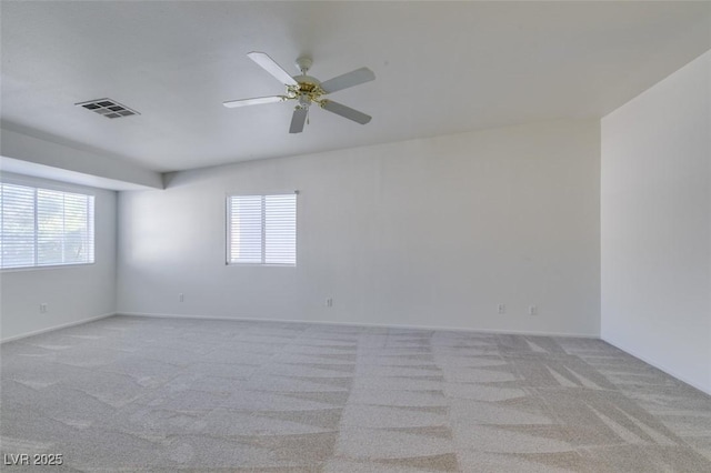 spare room with ceiling fan, plenty of natural light, visible vents, and light colored carpet